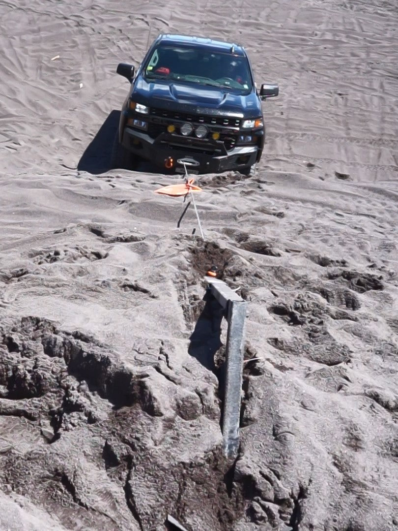 Redridge Industries' self-recovery anchor point (GRP) deployed in stamp sand, with a Redridge truck being pulled up a step grade.